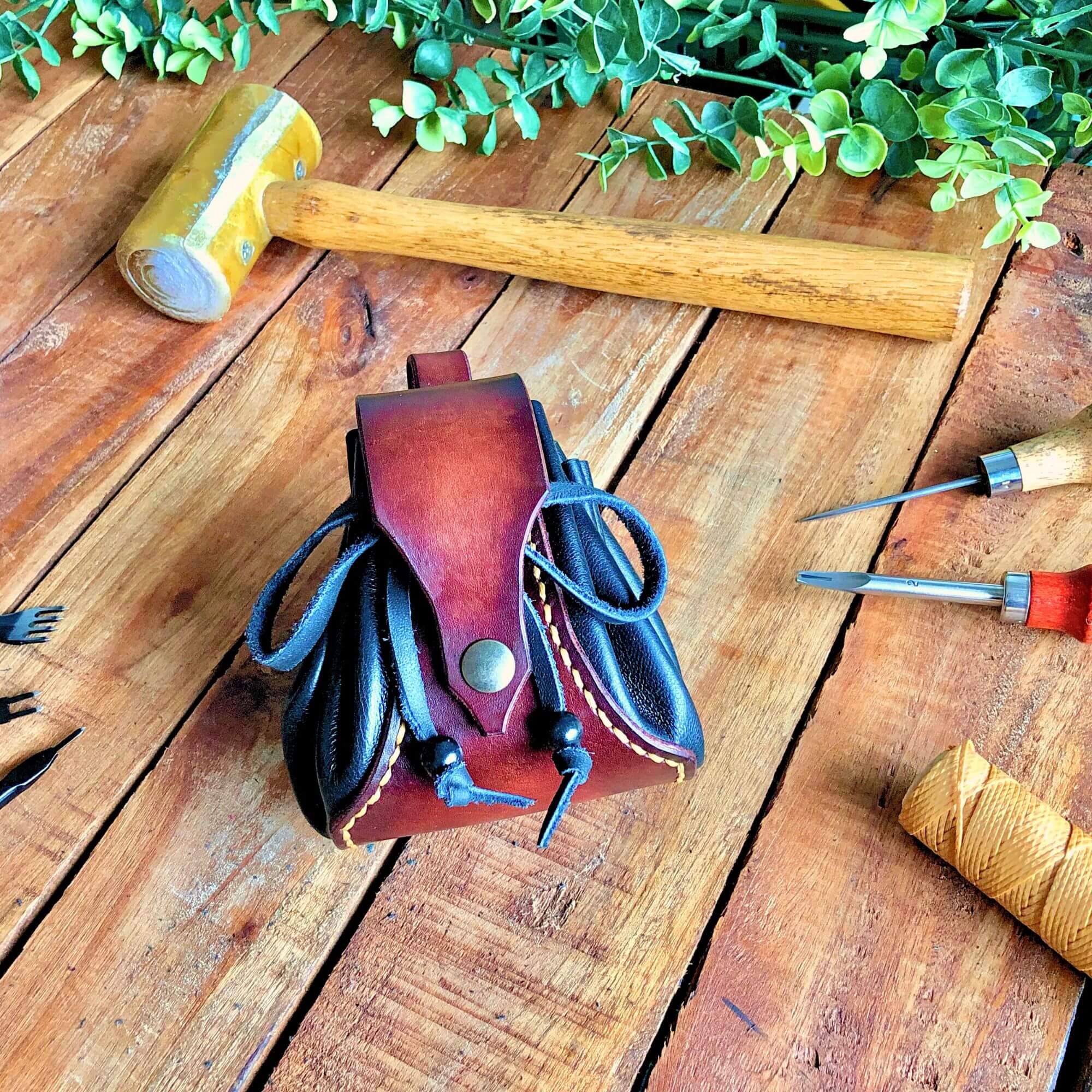 leathercraft tools with a drawstring dice pouch on a wooden backgound