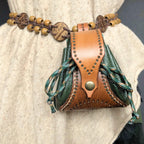 Handmade leather drawstring pouch with decorative elements on a person wearing a light-colored garment.