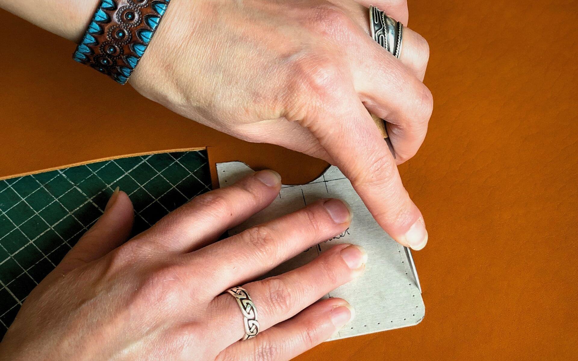 hands tracing a leathercraft pattern on to leather with an awl