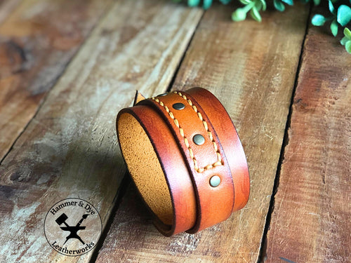 Aged-look cognac leather cuff bracelet with a hand-stitched strap and studs