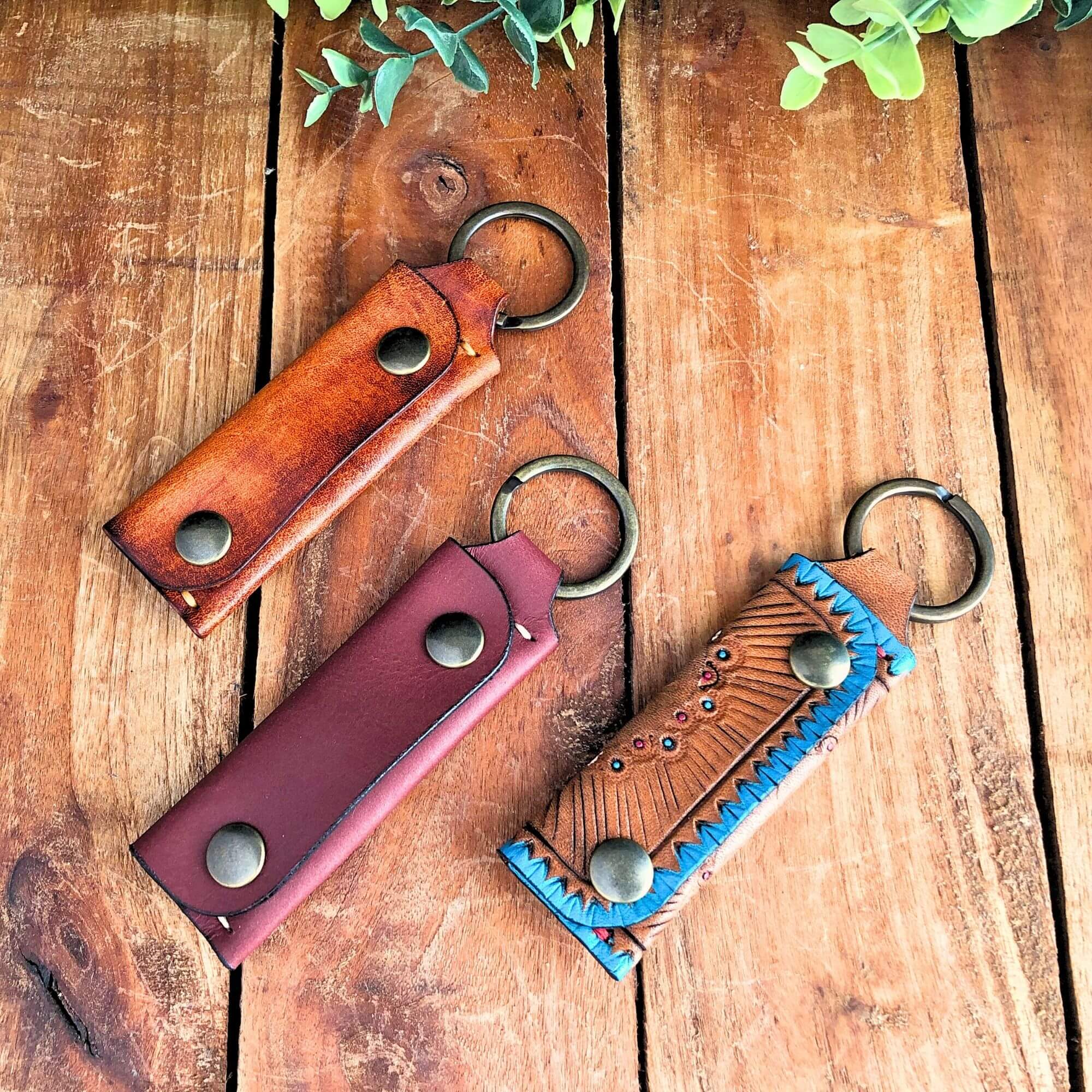 3 different Leather Emergency Keychain Wallets on a wooden surface