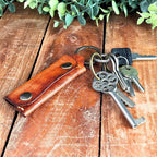 Leather Emergency Keychain Wallet attached to keys on a wooden surface