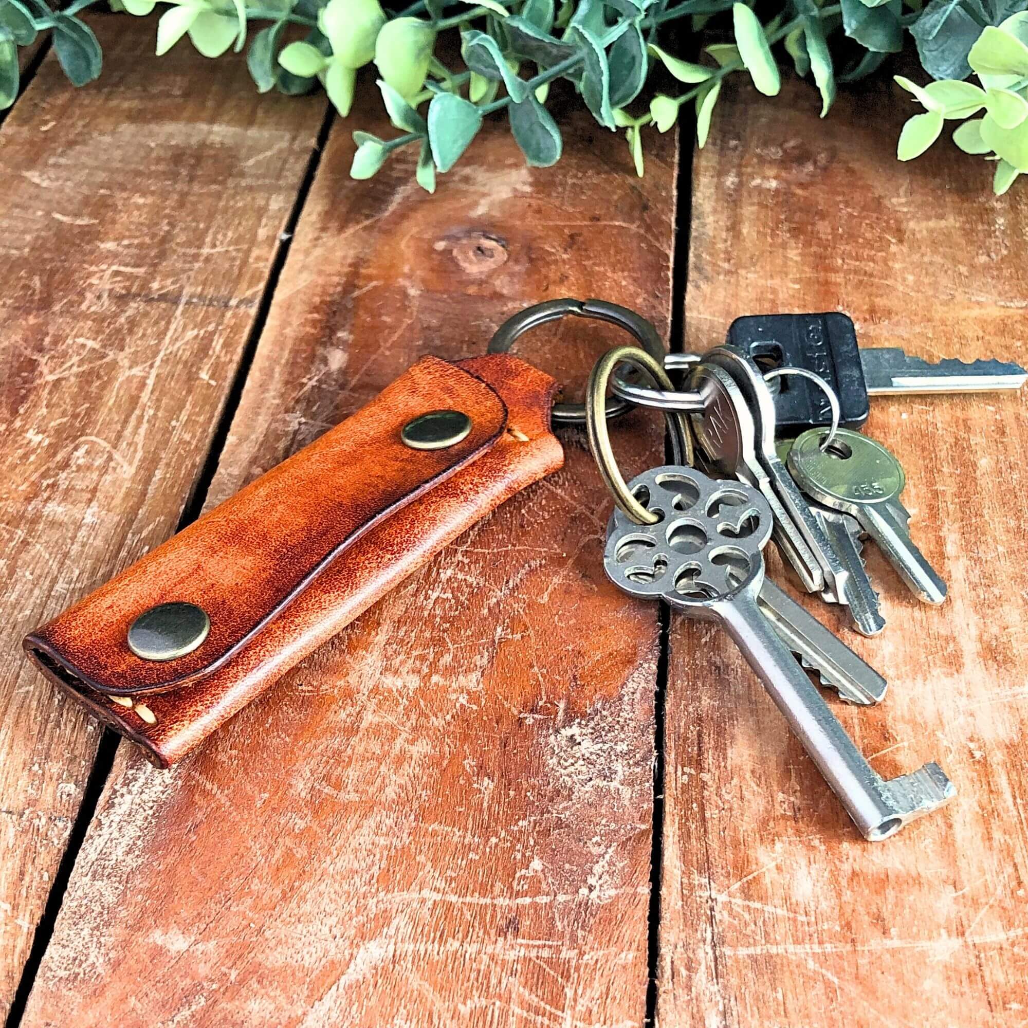 Leather Emergency Keychain Wallet attached to keys on a wooden surface