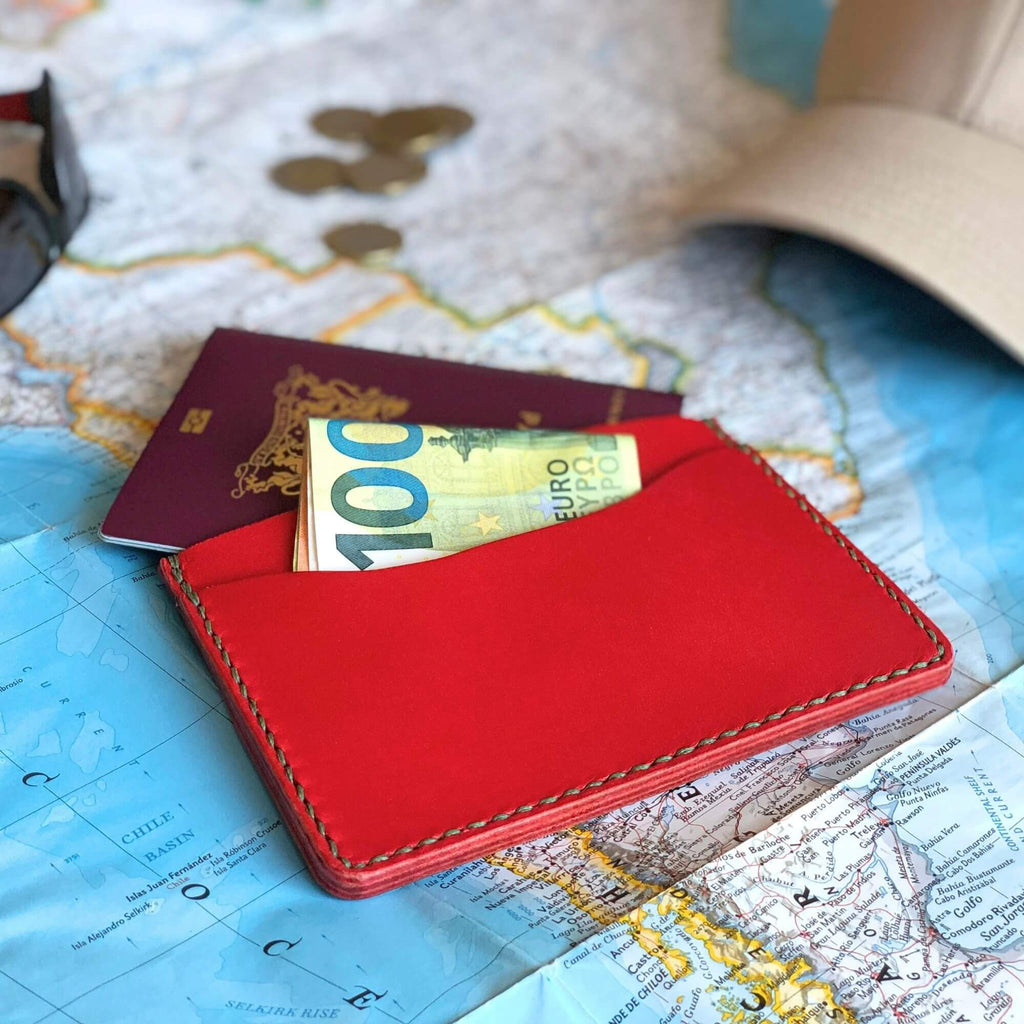 Red passport wallet with money on a world map