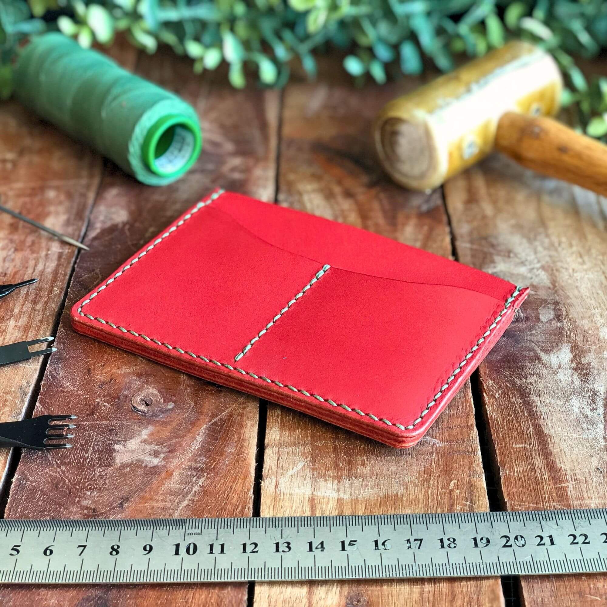 Red leather passport cover on a wooden surface with tools and a ruler