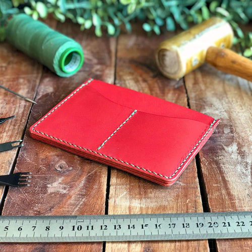 Red leather passport cover on a wooden surface with tools and a ruler