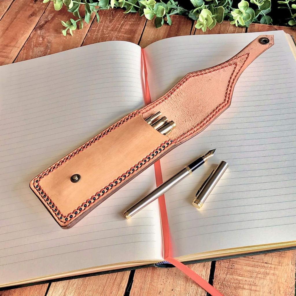 Leather pen holder with fountain pen on an open notebook