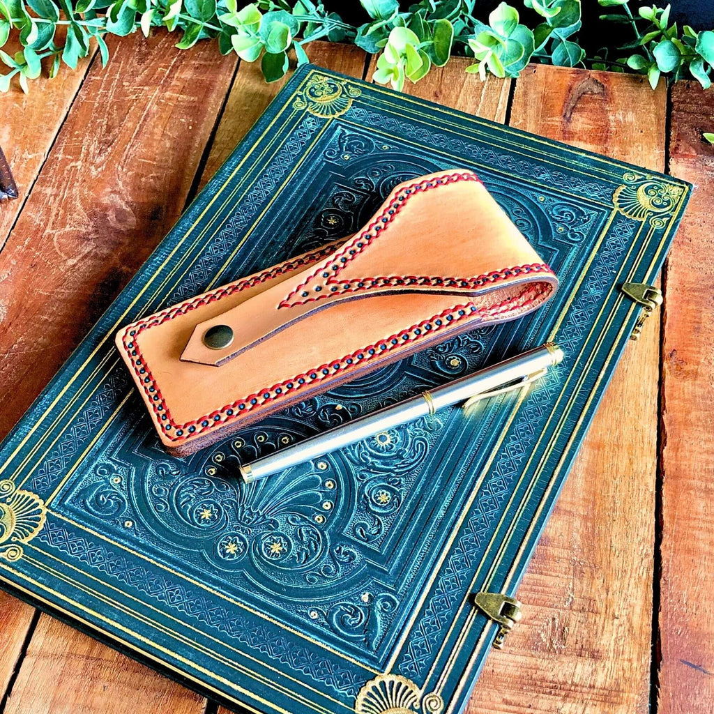 Decorative blue book with a leather pen pouch and pen on a wooden surface