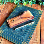 Decorative blue book with a leather pen pouch and pen on a wooden surface