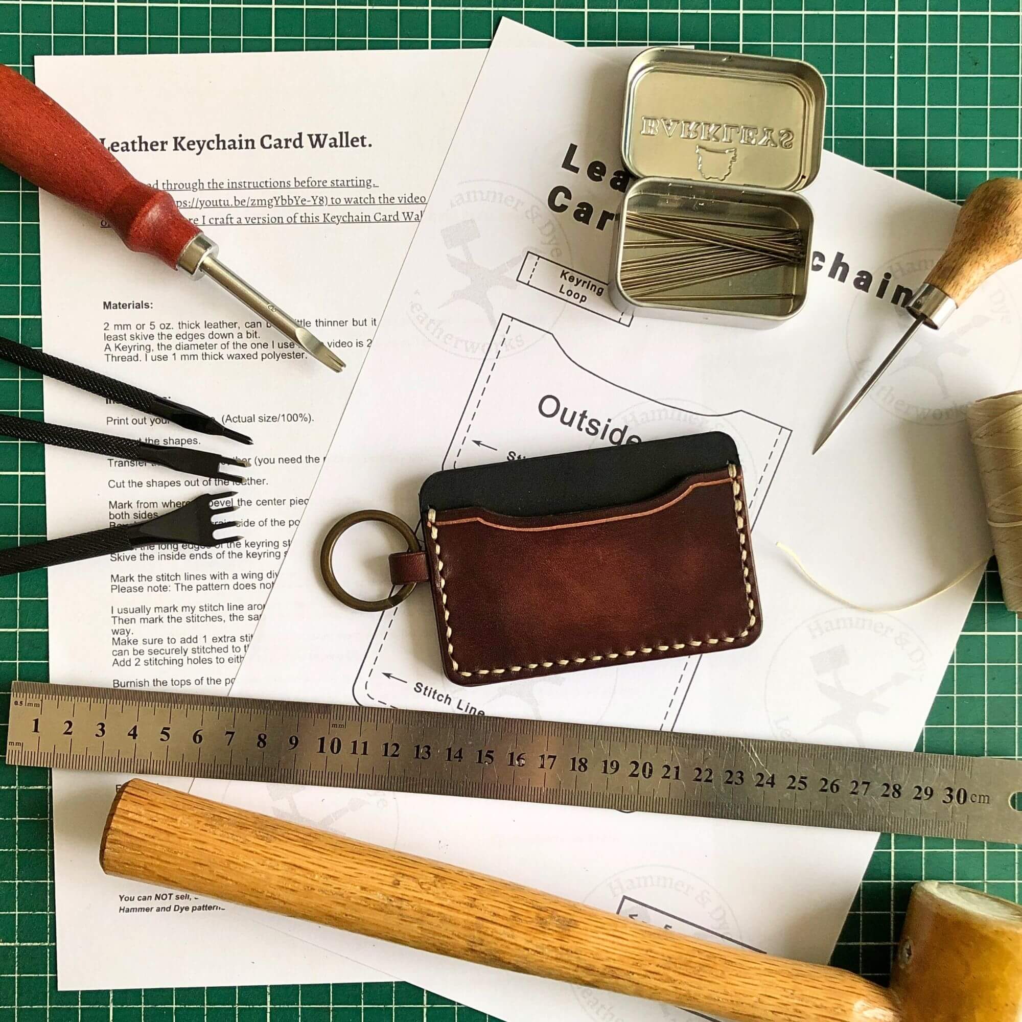 leather keychain card wallet on a printed leathercraft pattern surrounded by leathercraft tools