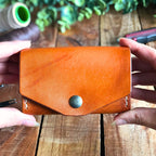 handmade leather wallet with a coin pocket held in 2 hands