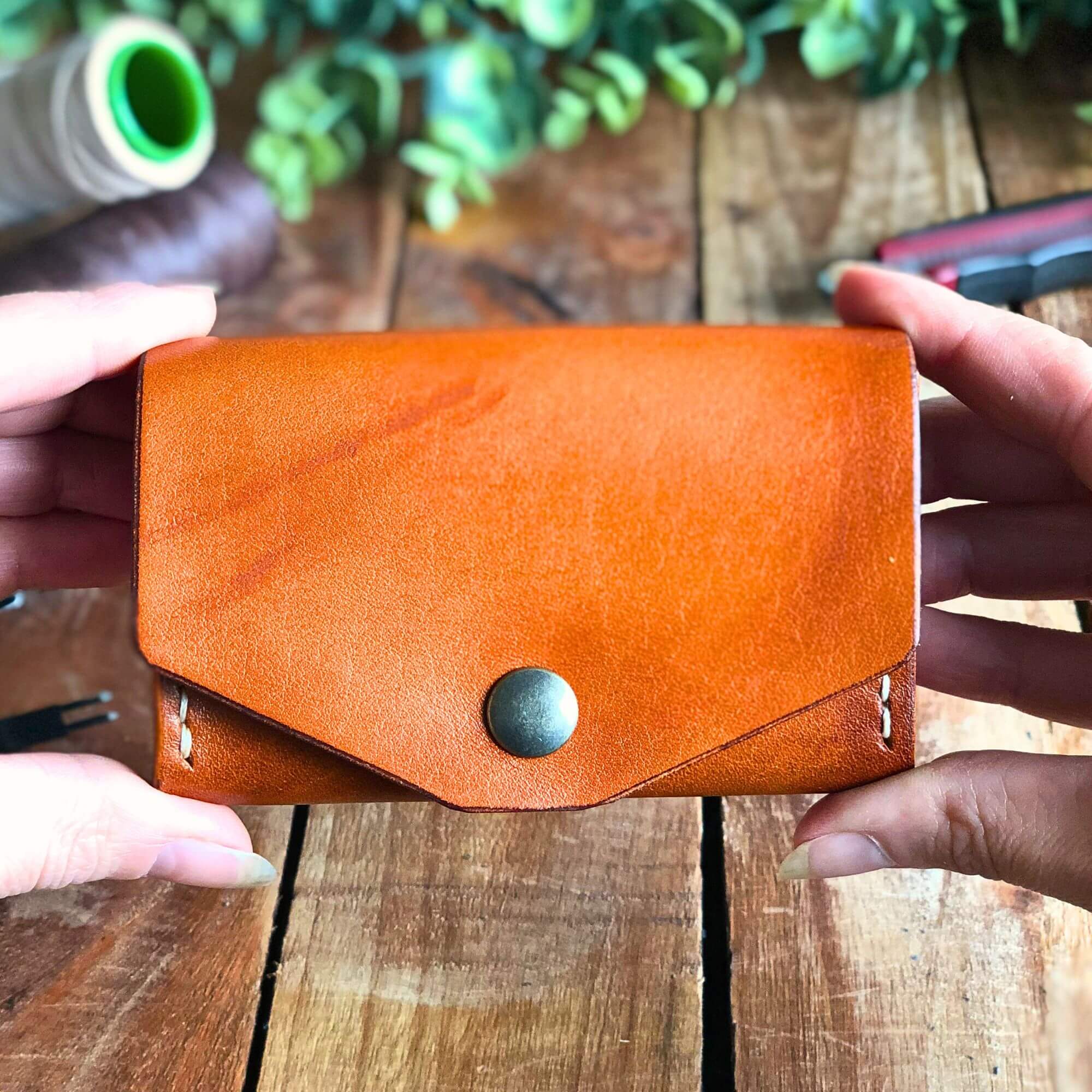 handmade leather wallet with a coin pocket held in 2 hands