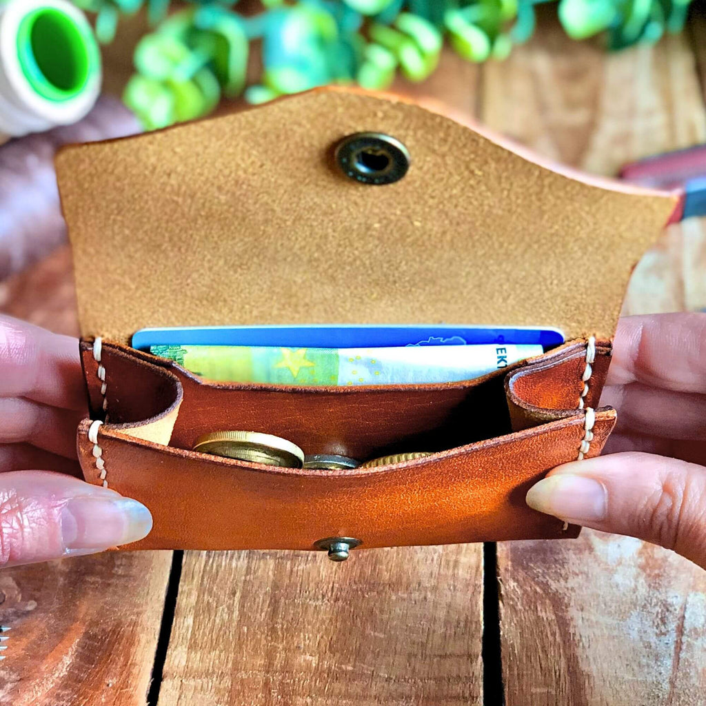 small leather wallet with coin and card pockets held open with money inside