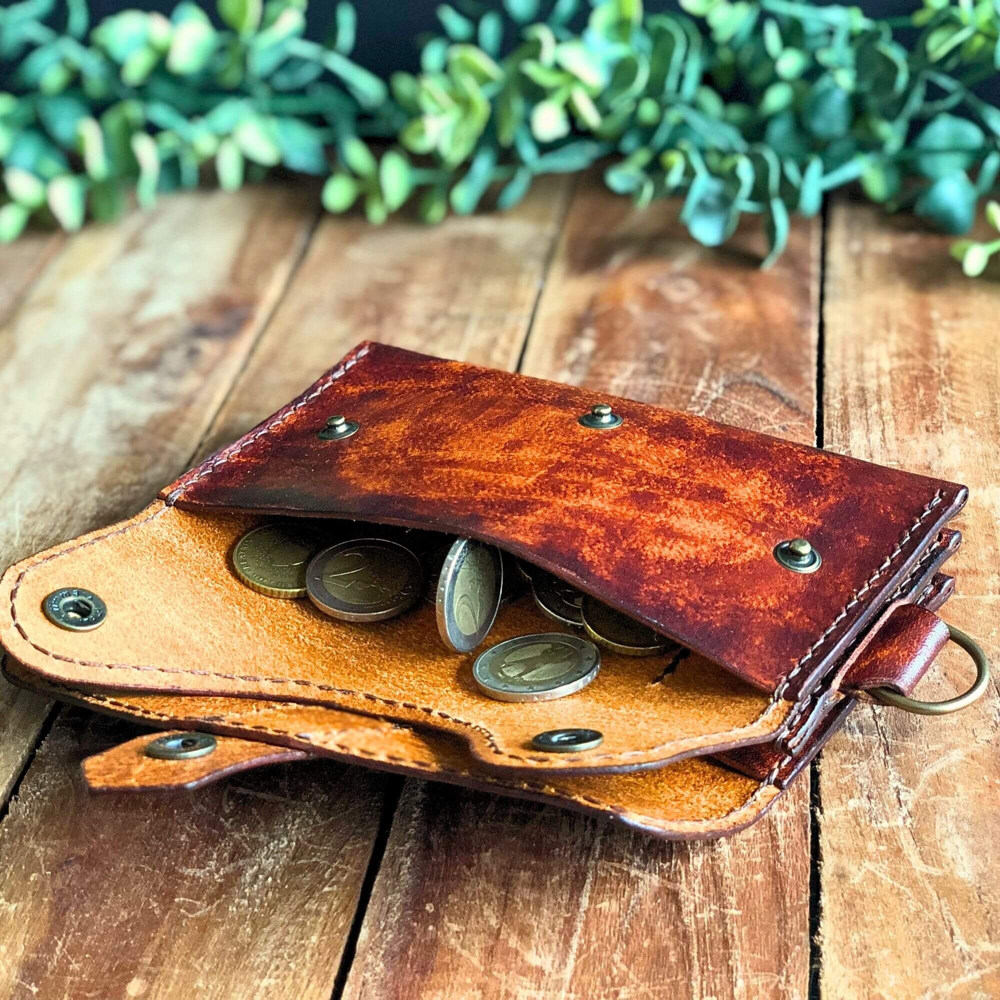 Dispatch Wallet leather PDF pattern, finished wallet laying on wooden planks with green foliage background